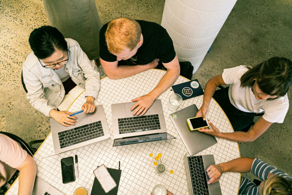 group of people in a table working with laptop and their phone